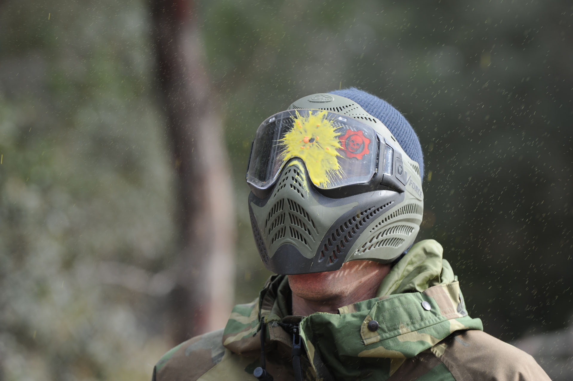 Paintball mask splattered with yellow paint after a direct hit