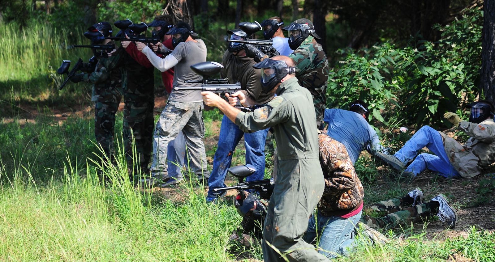 A group of players gearing up for paintball in the trees